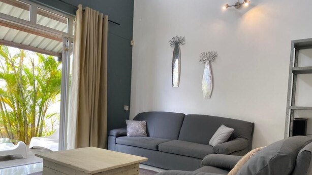 Ein modernes Wohnzimmer mit einem grauen Sofa, einem Holztisch und zwei an der Wand befestigten Vasen.
