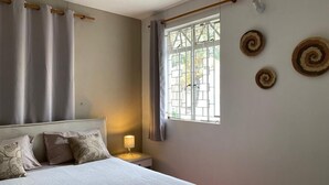 Ein Schlafzimmer mit Bett, Nachttisch, Fenster mit Vorhängen und Wanddekoration.