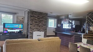 A living room with a TV, sofa, and a kitchen area with a staircase. - Desconexión y Tranquilidad (Canoves y Samalus)