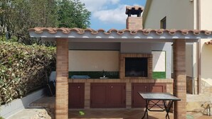 Una cuina exterior amb una xemeneia de maó, un rentaplat i una taula.
