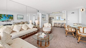A modern living room with a sofa, chairs, a glass coffee table, and a dining area with a table and chairs. - San Luis Beauty in The Beautiful San Luis Resort Pet Friendly (Galveston)