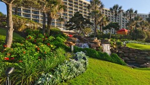 A hotel with a large building, a waterfall, and well-maintained gardens. - San Luis Beauty in The Beautiful San Luis Resort Pet Friendly (Galveston)