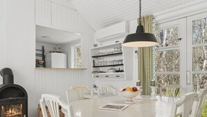 A dining area with a round table, white chairs, a black pendant light, and a fireplace. - "Lucie" - 50m from the sea by Interhome (Rønne)