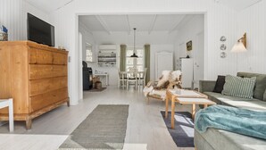A spacious living area with a wooden dresser, a sofa, a table, and a fireplace. - "Lucie" - 50m from the sea by Interhome (Rønne)