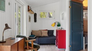 Une pièce chaleureuse avec un bureau en bois, un canapé bleu orné de coussins à motifs, une armoire rouge et une grande porte bleue.