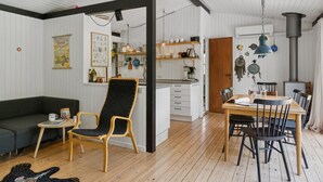 Un espace de vie moderne avec un plancher en bois, une chaise noire et jaune, une table à manger avec des chaises, et un coin cuisine doté d’étagères et d’une cuisinière.
