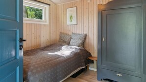 Une chambre à coucher avec un lit, une armoire, une fenêtre et un tableau encadré au mur.