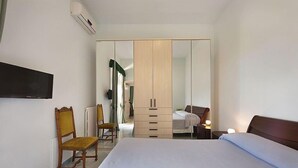 A hotel room with a bed, a wardrobe, a chair, a desk, and a television. - Casa Milli C: A cozy apartment situated on a promontory facing the sea. (Massa Lubrense)