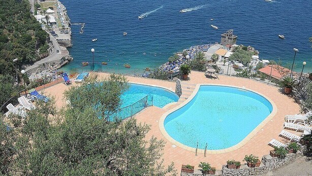 A resort with a large swimming pool, a beach area, and a view of the sea. - Casa Milli C: A cozy apartment situated on a promontory facing the sea. (Massa Lubrense)