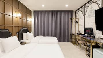 A hotel room with a large bed, a desk with a computer, and a TV.