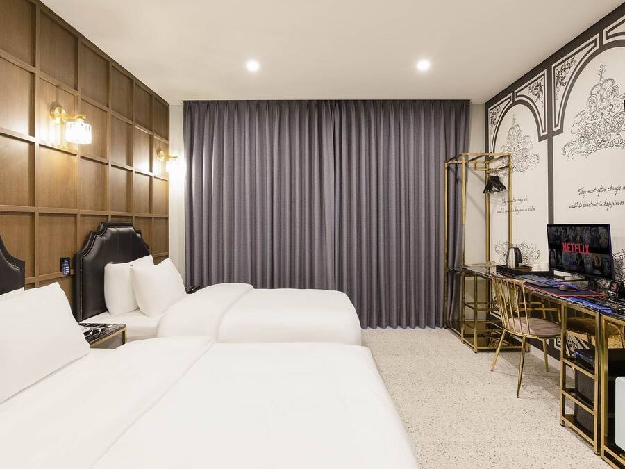 A hotel room with a large bed, a desk with a computer, and a TV.