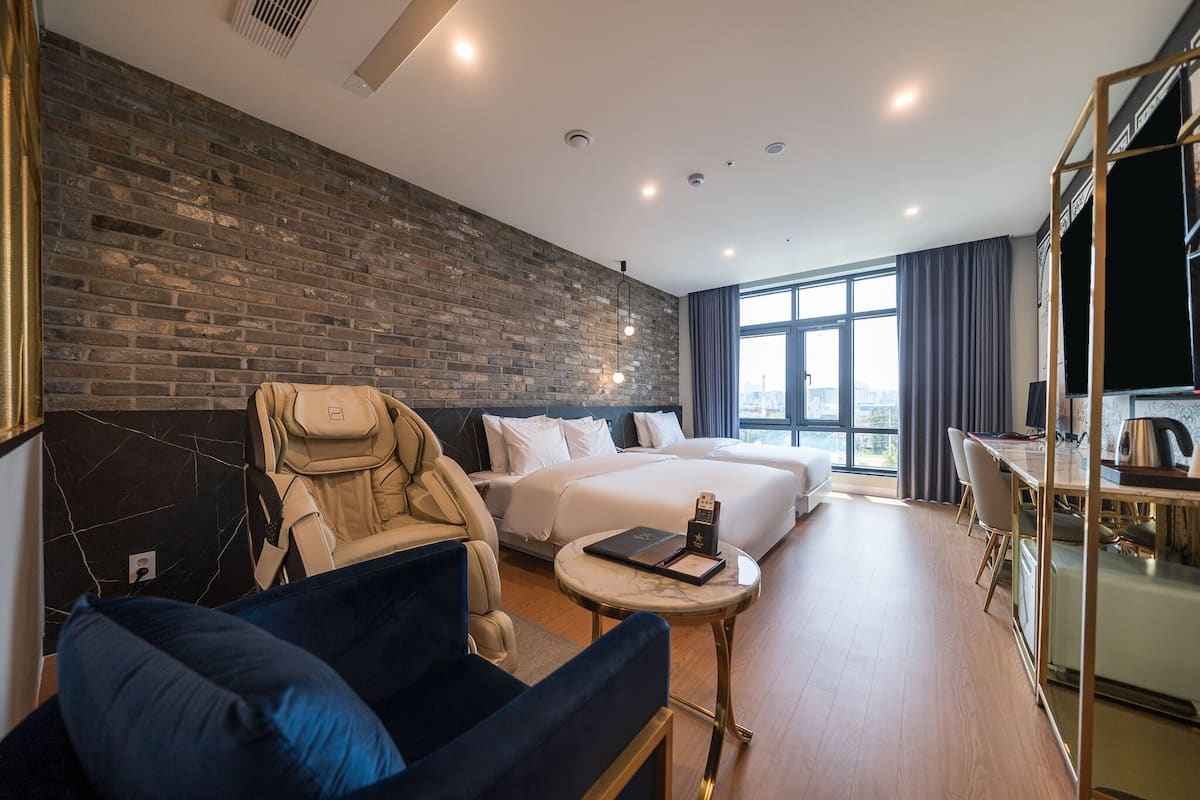 Et moderne hotelværelse med en murstensvæg, en stor seng, en sofa, et skrivebord og udsigt over byen.
