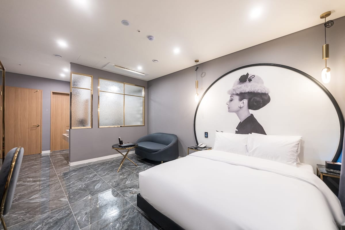 Et moderne hotelværelse med en stor seng, et rundt spejl, en stol og et skrivebord.