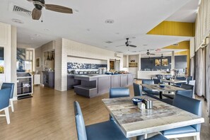 A modern kitchen with white subway tiles, a central island, and a dining area with blue upholstered chairs and a wooden table.