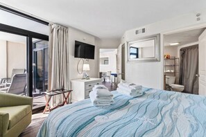 A hotel room with a bed, a desk, a chair, a television, and a bathroom.