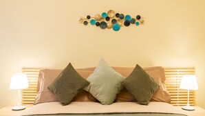 A bed with three pillows, a wall art piece above it, and two bedside lamps on either side.