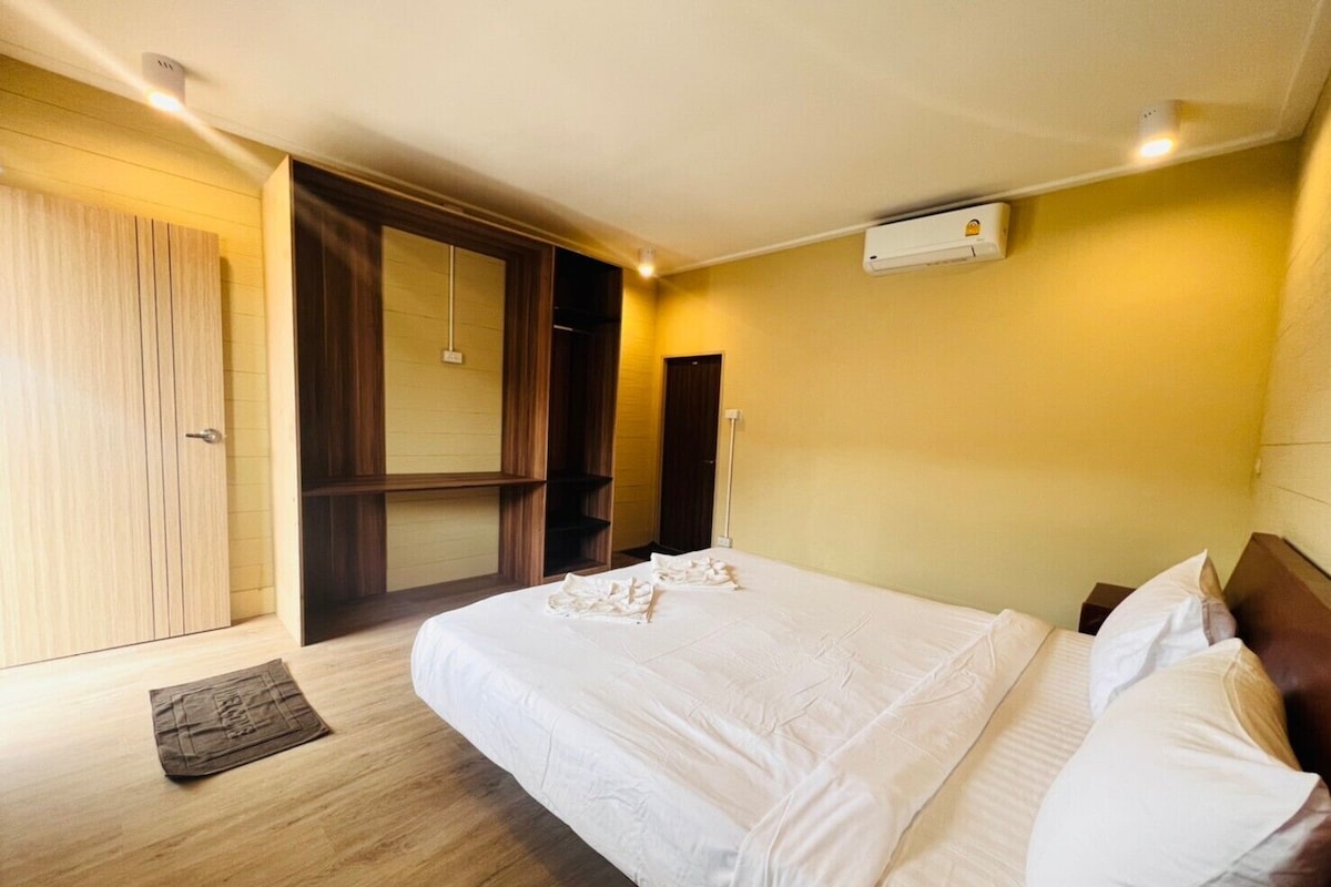 Habitació d'hotel amb un llit gran, terres de fusta, un armari i un armari encastrat.