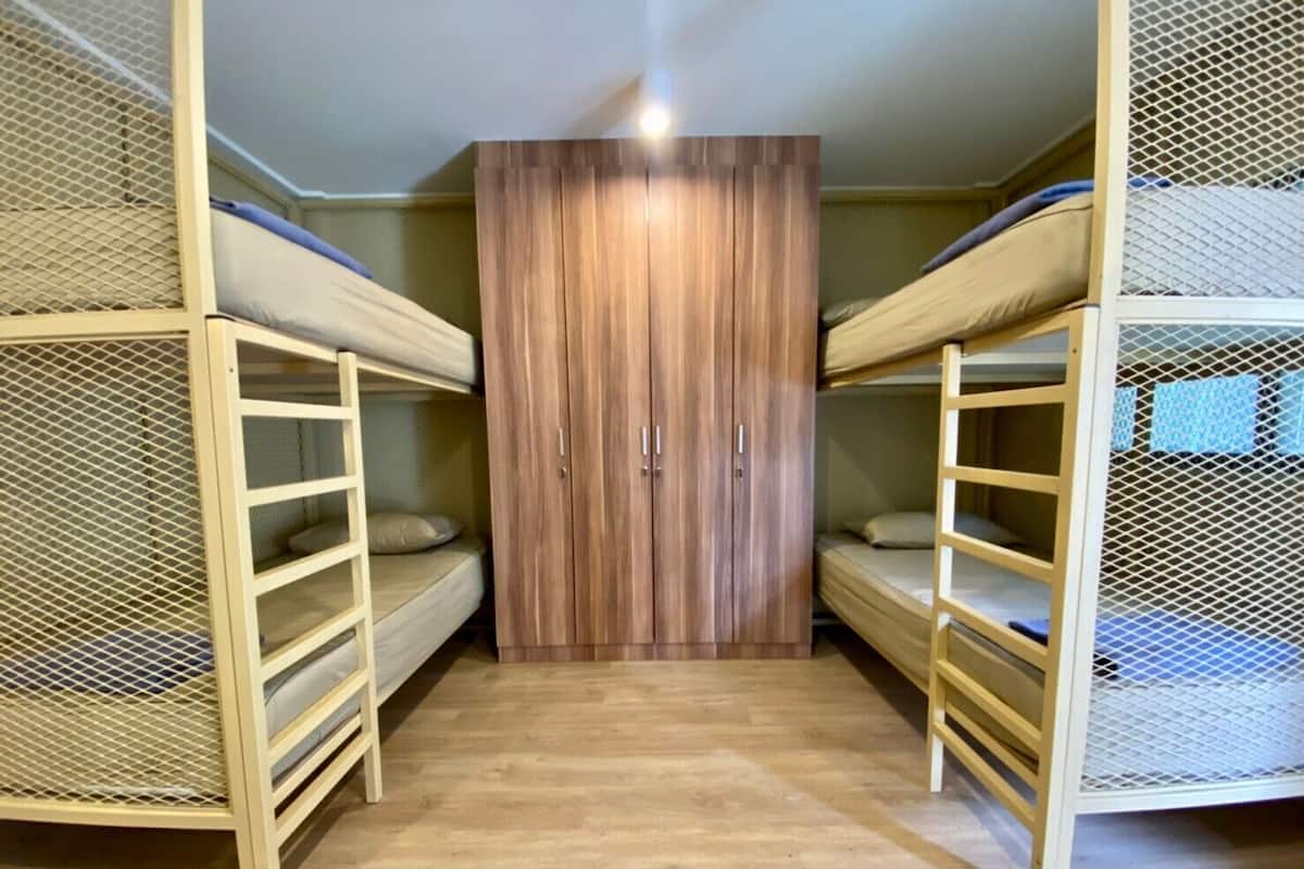 Um quarto com beliches, um guarda-roupa e piso de madeira.