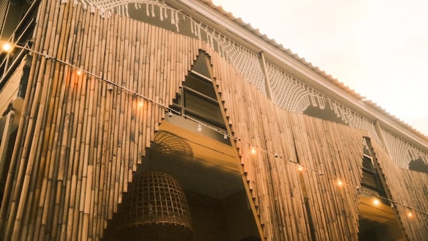A building facade with vertical bamboo panels and a series of arched openings. - U're Holitel  (Ko Pha-ngan)