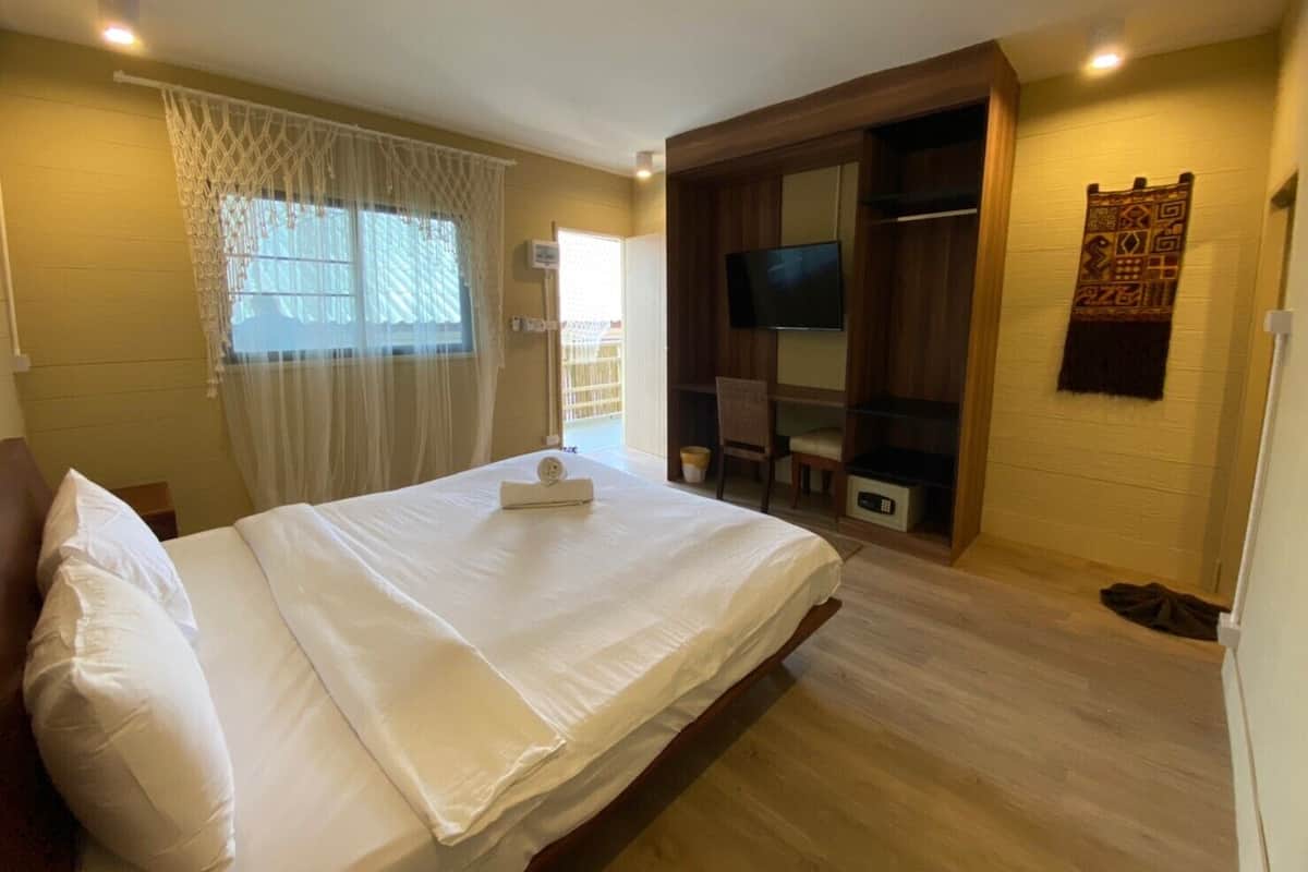 Quarto com cama, televisão, cadeira e guarda-roupa de madeira.