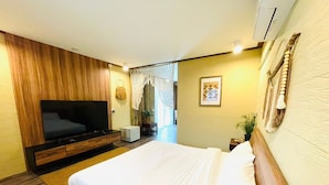 A modern hotel room with a large bed, a TV, a small table, and a plant. - U're Holitel  (Ko Pha-ngan)