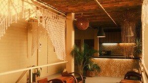 A cozy, rustic interior with wooden beams, macramé wall hangings, and a wooden reception desk. - U're Holitel  (Ko Pha-ngan)
