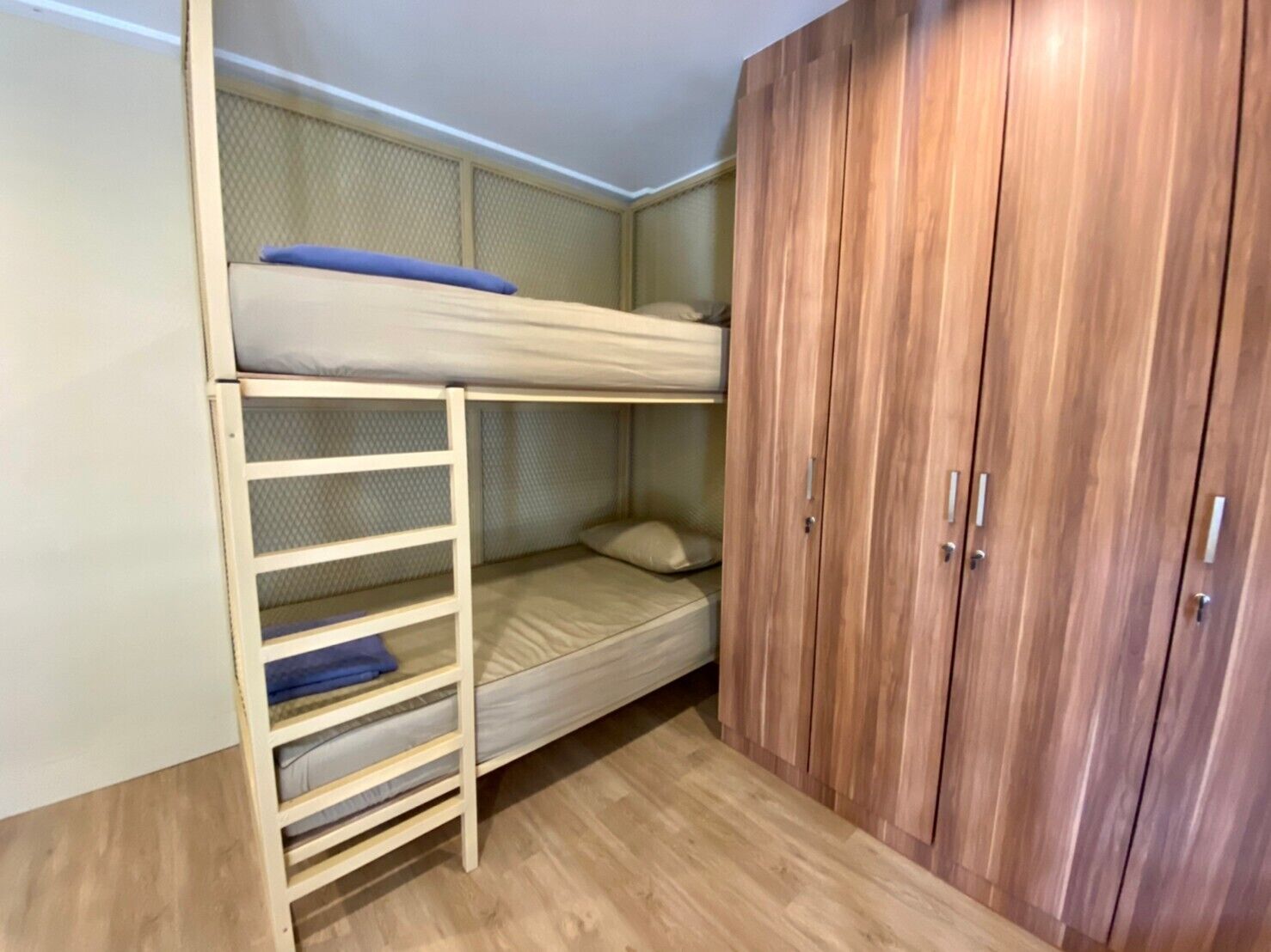 Una cama litera con una escalera, un armario y un colchón en el suelo.