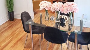 Ein Essbereich mit Holzboden, schwarzen Stühlen und rosa Blumen in Vasen.