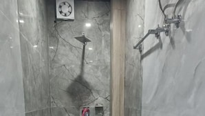 A compact bathroom with a toilet, a shower, and a small sink.