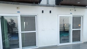 A building with two large glass doors, each with a metal mesh screen. There are two small signs above the doors, one with the number 102 and another with the number 103.