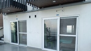 A building with three large glass doors, a metal staircase, and a number '101' sign.