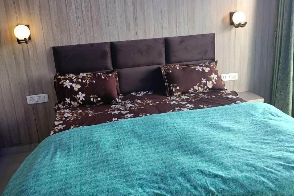 A bedroom with a wooden headboard, floral bedding, and two wall-mounted lights.