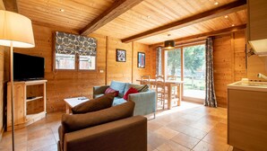 L'intérieur d'un chalet en bois, avec un téléviseur, un canapé et un coin repas.
