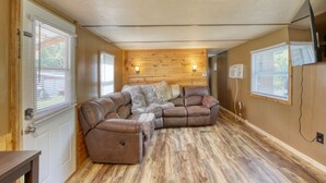 Una habitación acogedora con un sofá seccional de cuero marrón, paredes de madera y suelo de madera.