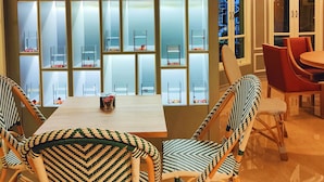 A dining area with a wooden table and wicker chairs, surrounded by a wall of glass aquariums. - Siri Ratchadamnoen Bangkok Hotel (Bangkok)