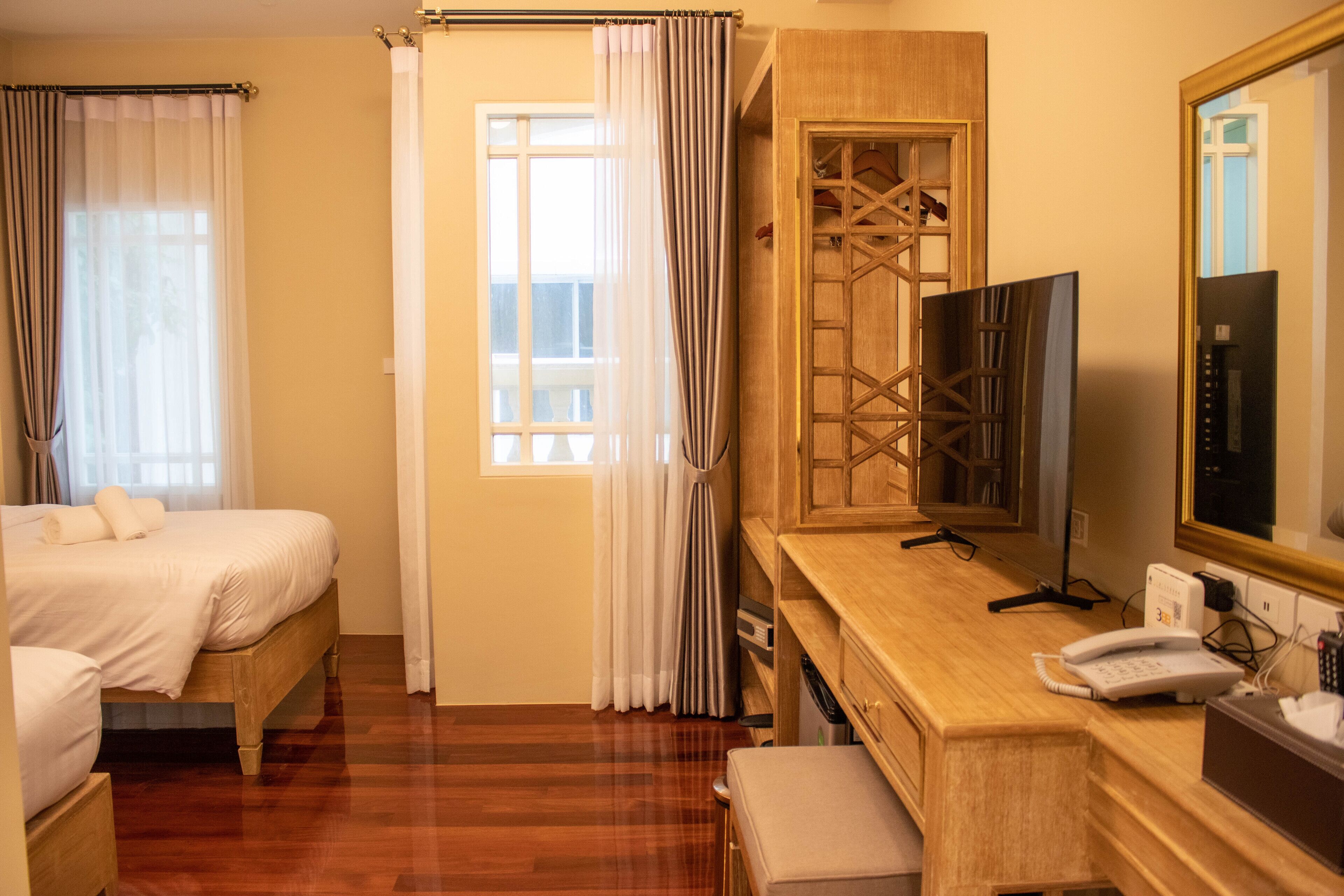 A hotel room with a bed, a desk with a telephone, a television, and a mirror.