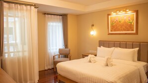 A hotel room with a large bed, a chair, a nightstand, and a wall-mounted light fixture. - Siri Ratchadamnoen Bangkok Hotel (Bangkok)