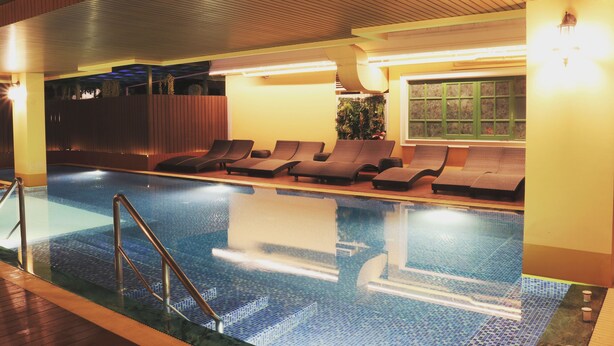 An indoor swimming pool with lounge chairs and a wooden ceiling. - Siri Ratchadamnoen Bangkok Hotel (Bangkok)