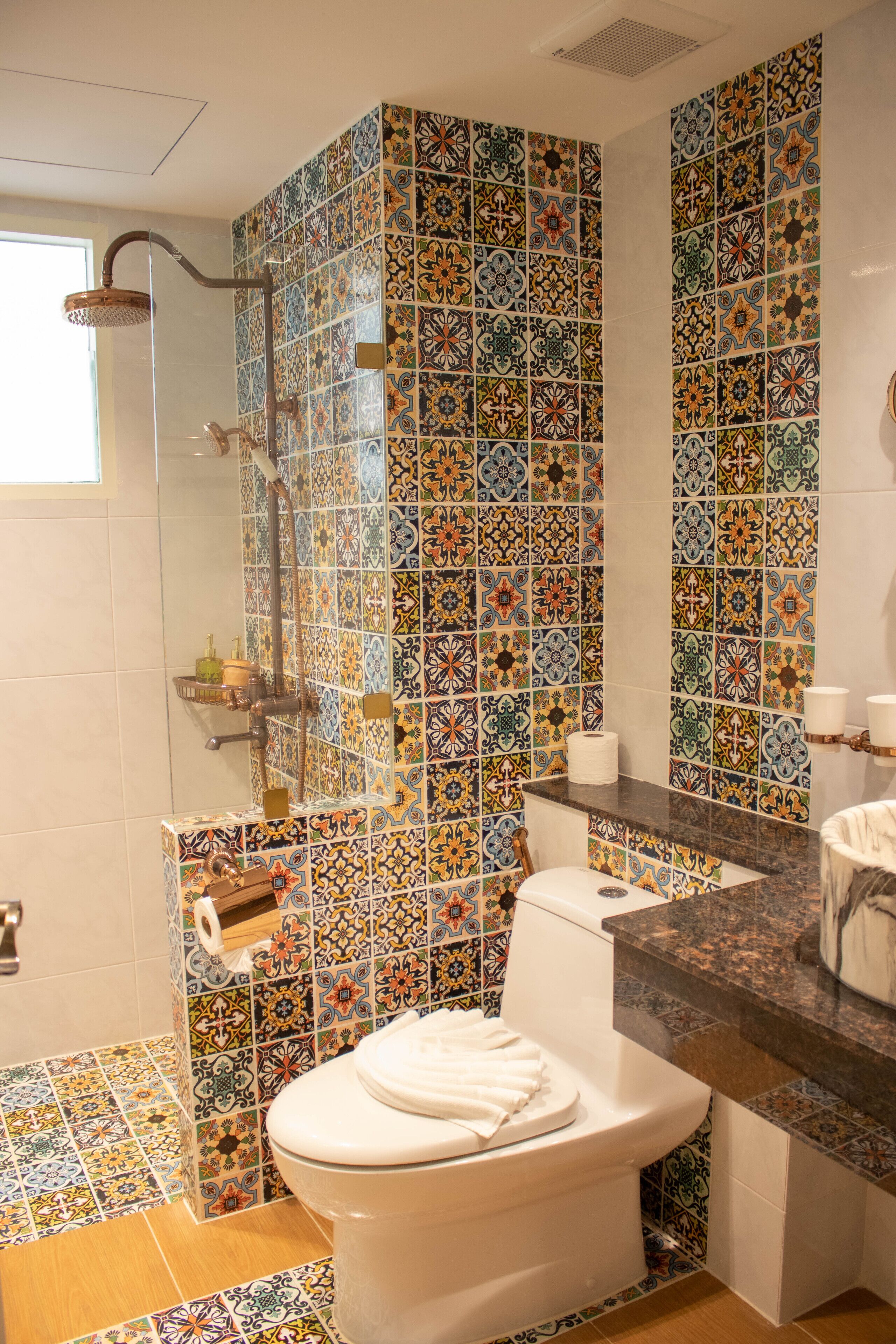 A bathroom with a tiled shower, a toilet, and a sink with a marble countertop.
