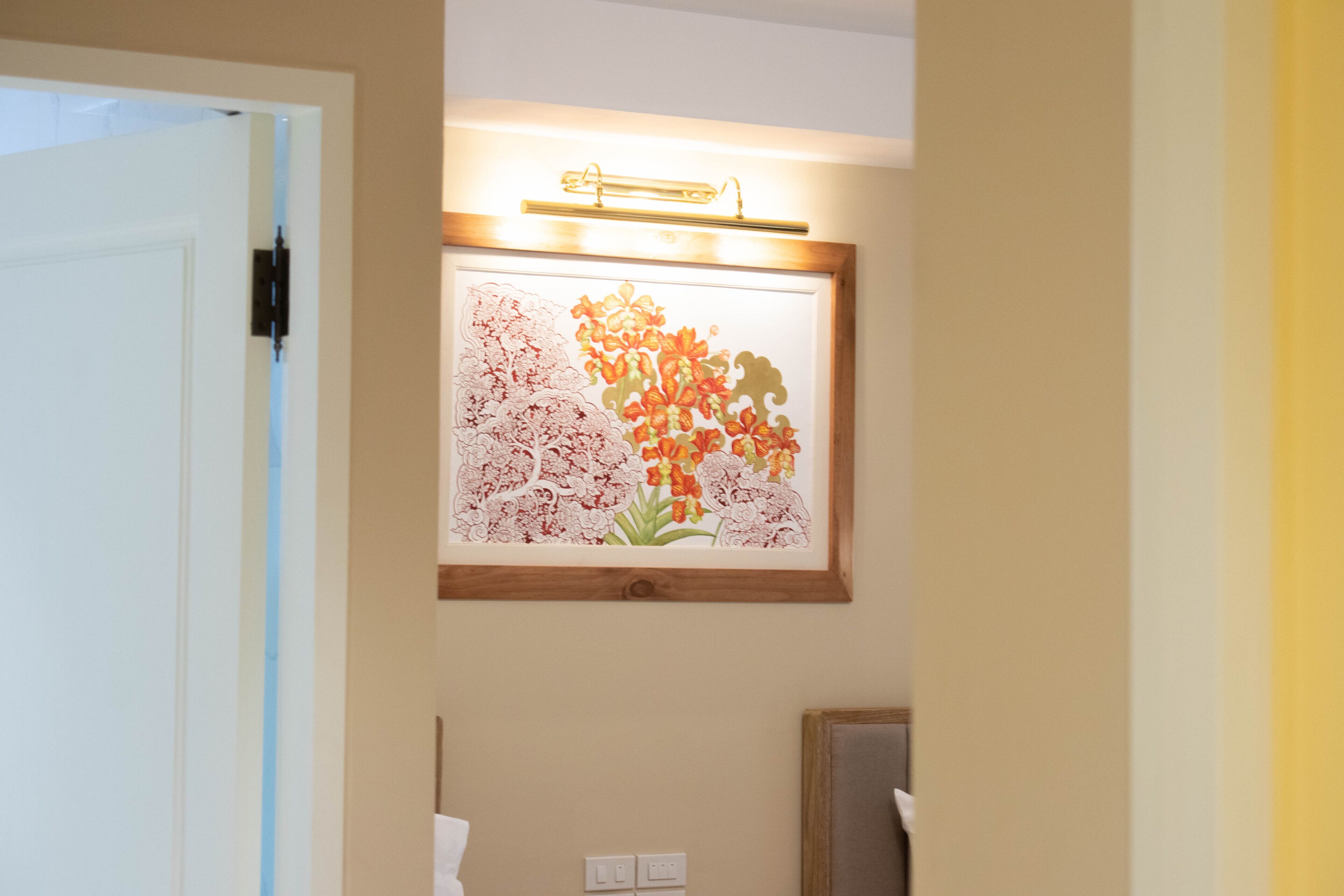 A framed floral artwork on a wall above a mirror.