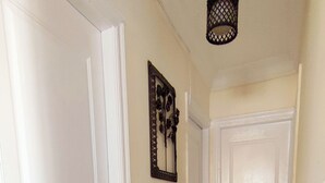 A hallway with white doors, a wall-mounted light fixture, and a door with a circular design.