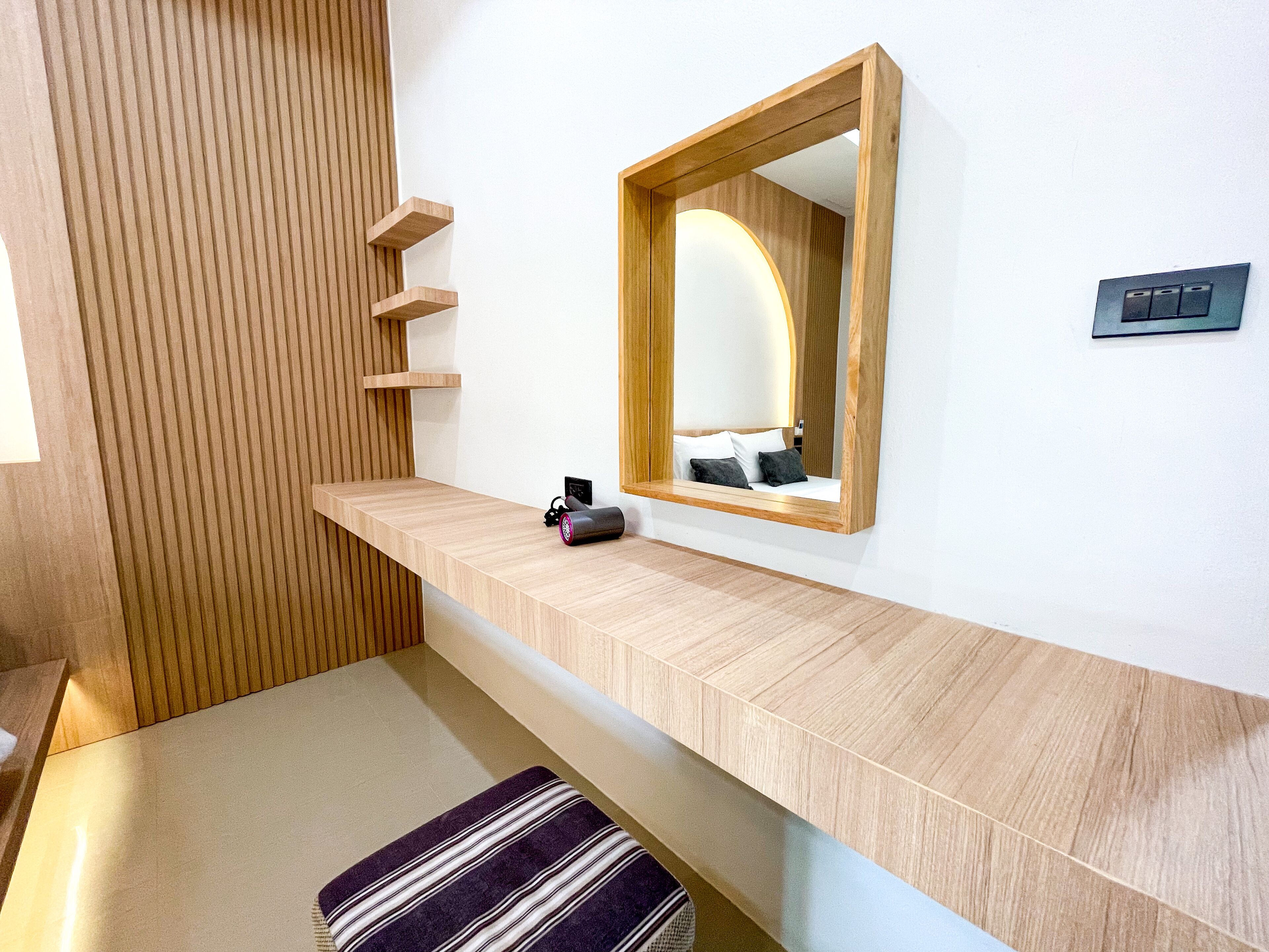 A modern bathroom with a wooden vanity, a mirror, and a towel bench.