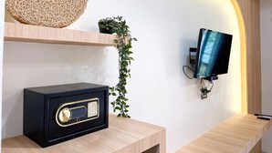 A modern room with a wooden console table, a black radio, a wall-mounted TV, and a decorative woven piece above the table. - Dara Homestay Koh Kood (Ko Kood)