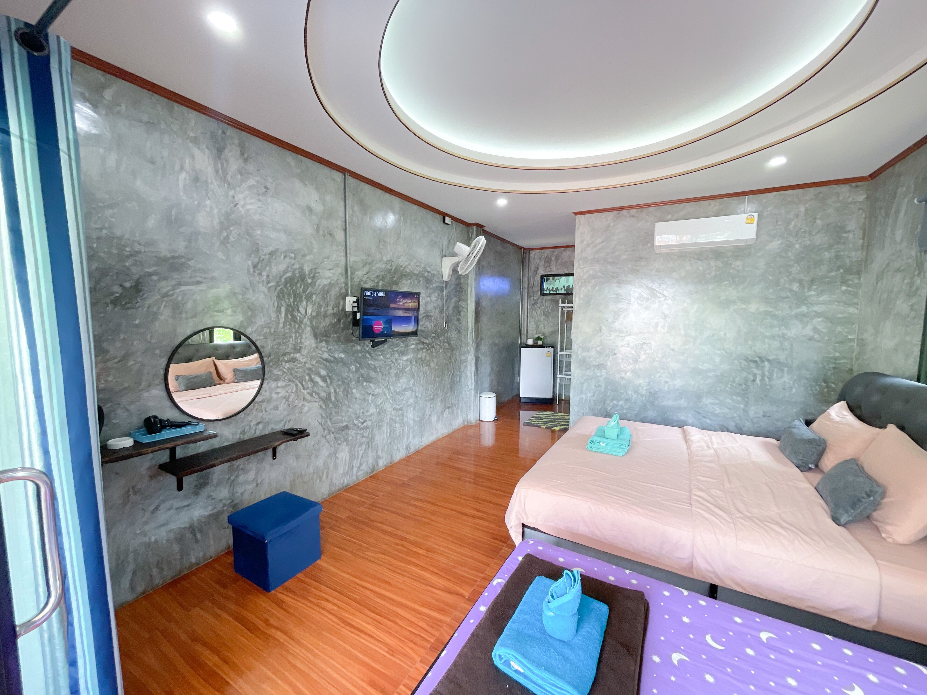 Una habitación de hotel moderna con una cama, un televisor, un espejo y un escritorio pequeño.