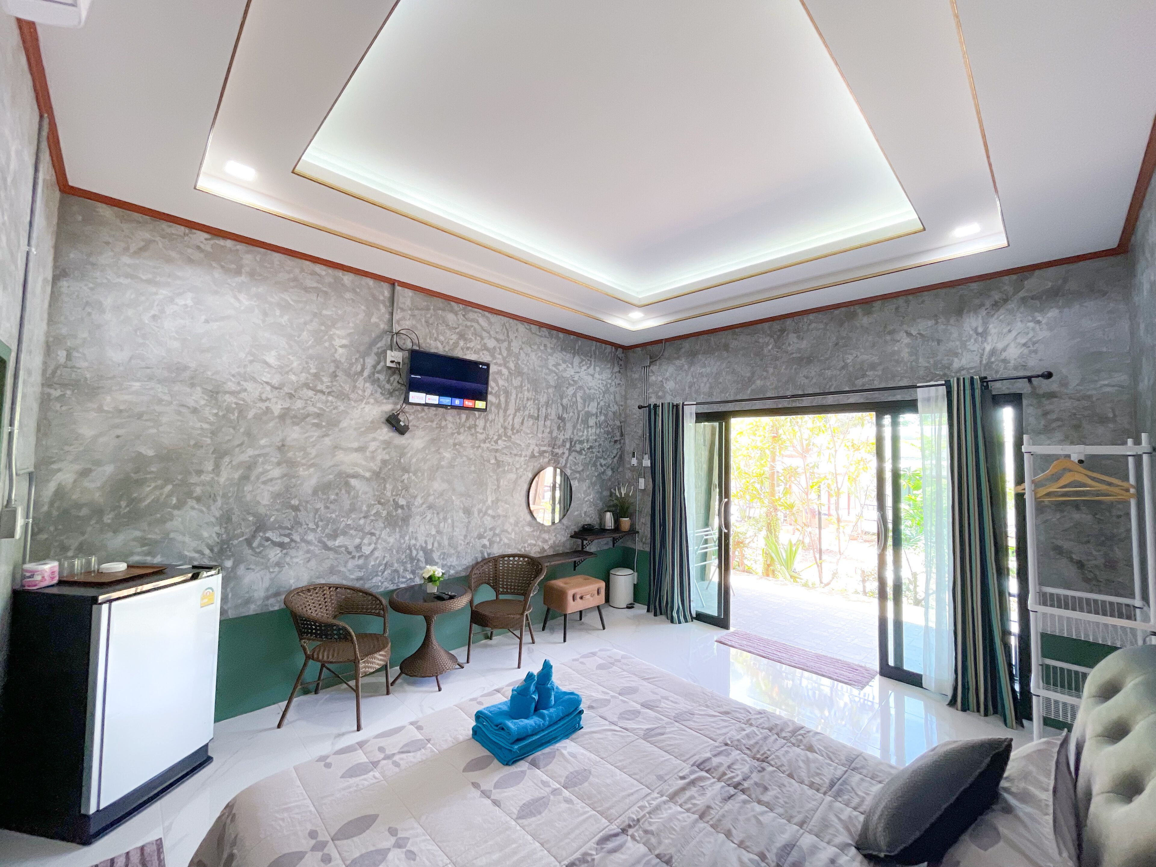 A modern hotel room with a bed, a desk, a television, and a view of the outdoors.