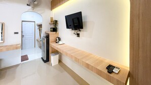 A modern reception area with a flat-screen TV mounted on the wall, a small trash bin, and a coffee maker on a wooden counter. - Dara Homestay Koh Kood (Ko Kood)