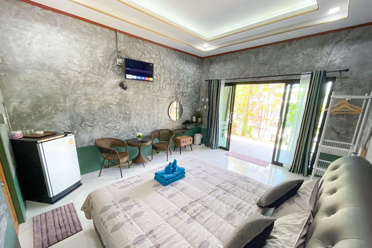 A hotel room with a bed, a desk with chairs, a television, and a view of the outdoors.
