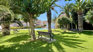 A well-maintained outdoor area with a pool, benches, and palm trees. - ESPLENDID 11 (Estartit)