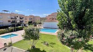 Un área residencial con piscina, un espacio de descanso cubierto al aire libre y un edificio con balcones.