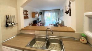 A kitchen with a double sink, wooden cabinets, and a view into the dining area. - ESPLENDID 11 (Estartit)